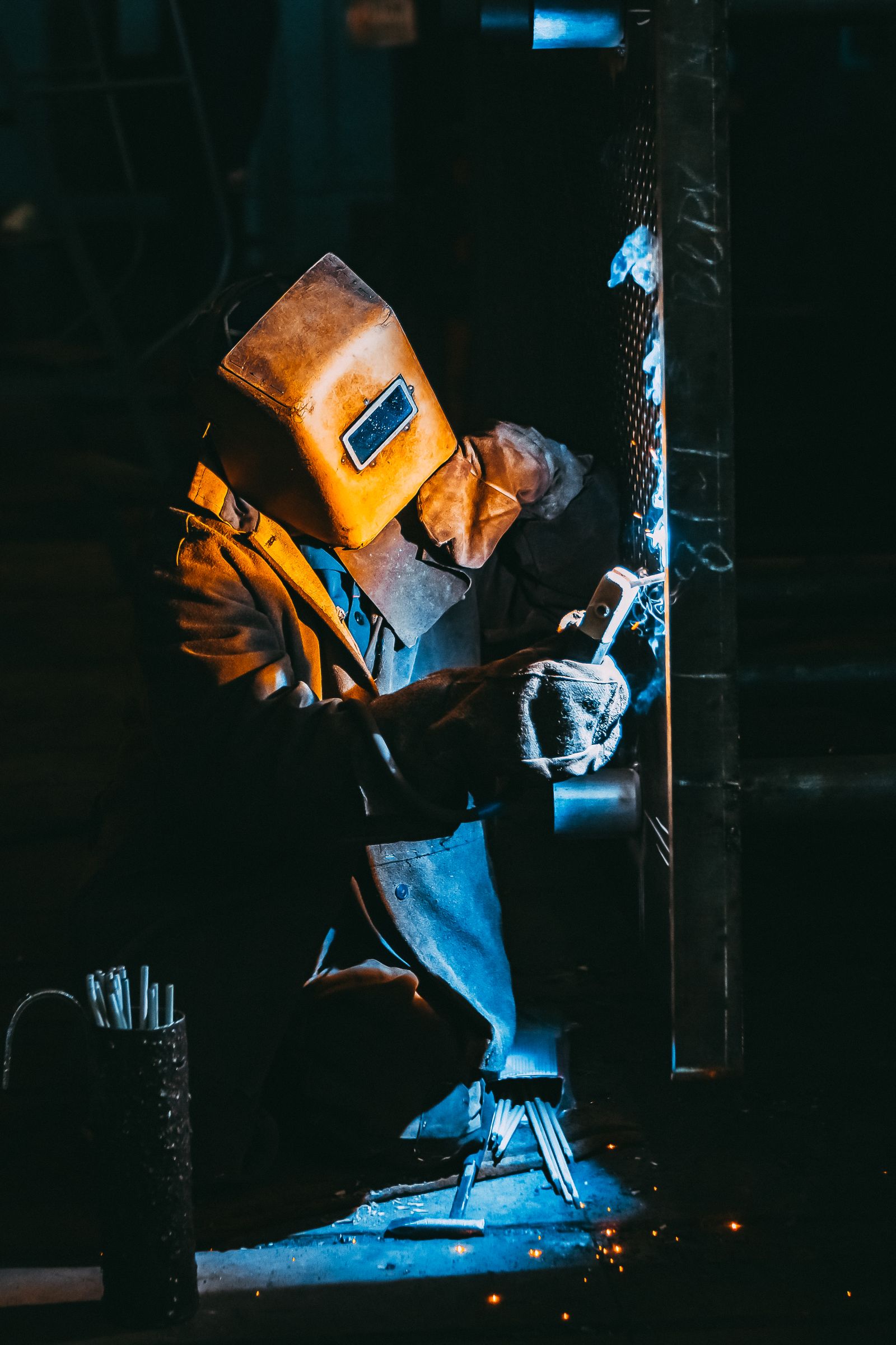 Certified welder joining metal on site while wearing protective gear