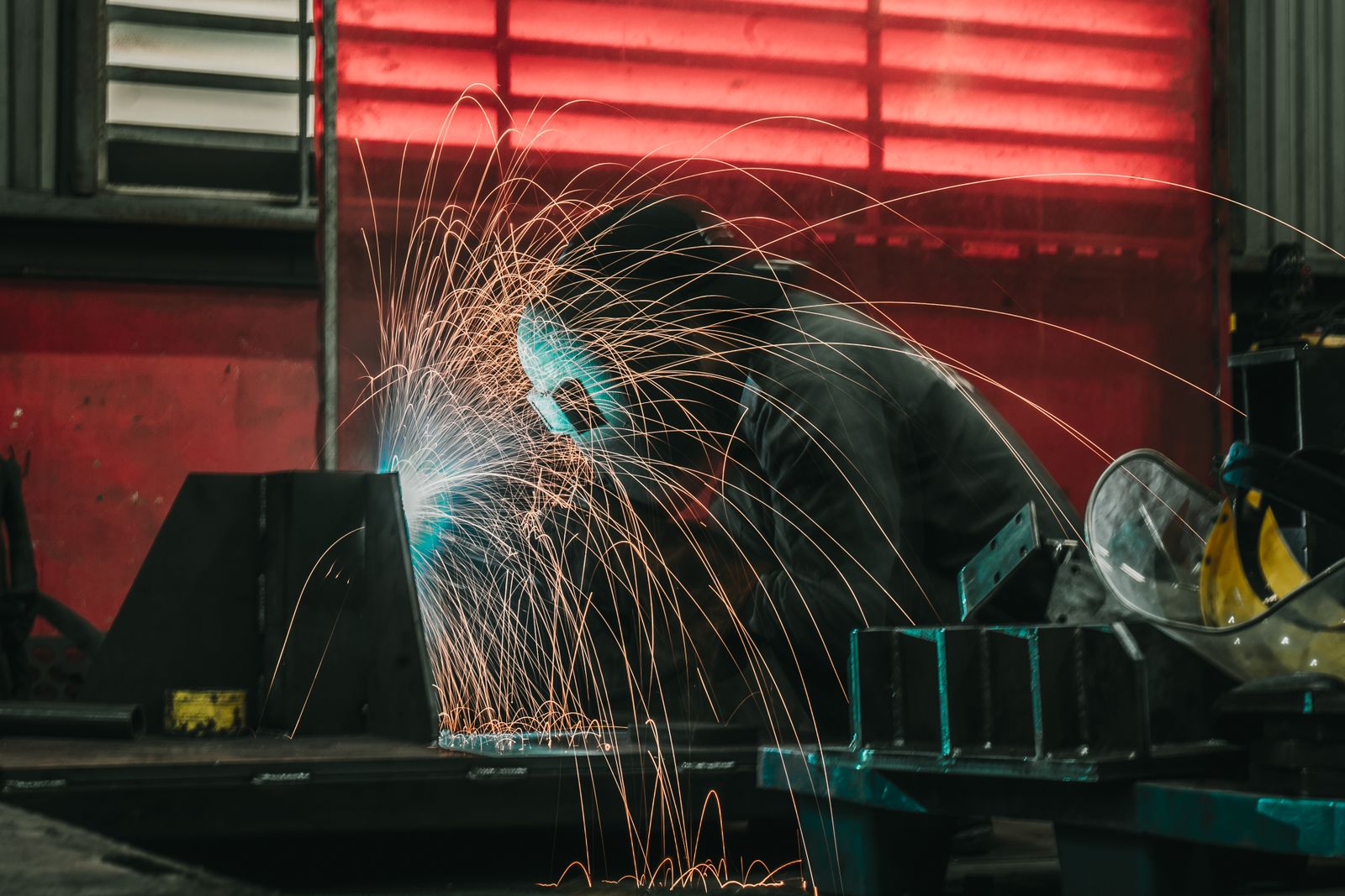 Welder producing sparks while fabricating steel in a workshop